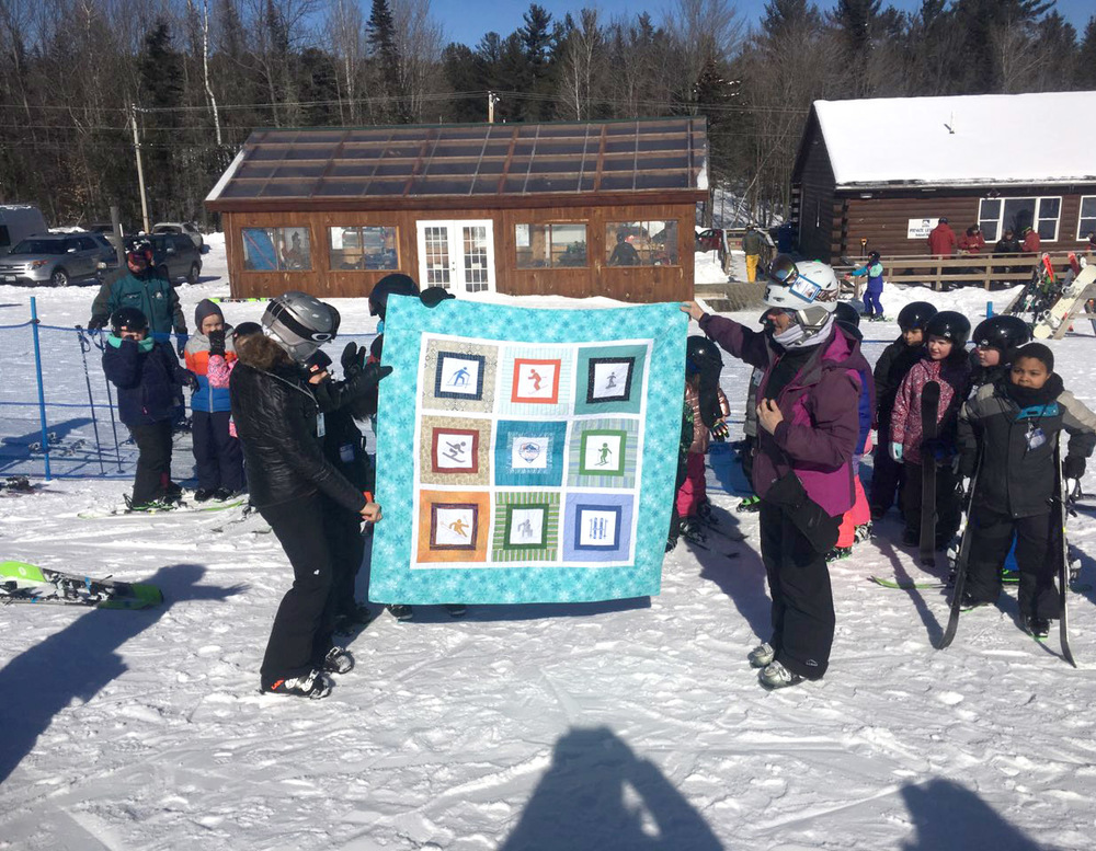 Mt. Abram Ski Club President Laurie Fitch and board member/ski instructor Shauna Schussler receive Dike Newell’s student quilt
