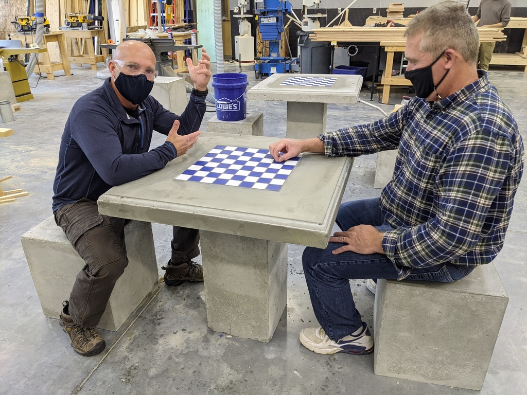 Two Bath Tech staff try out the seats and chess table made by students