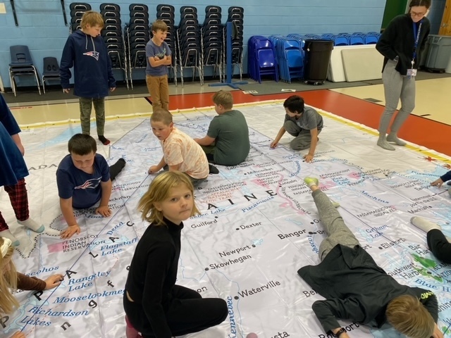 Gr 4 students standing/sitting on giant map