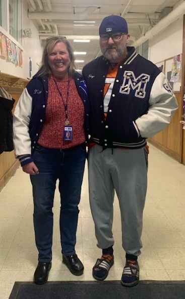 two adults wearing letterman's jackets from their high school days