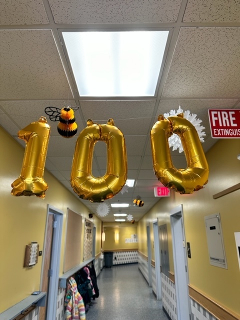 100th day of school gold balloons hanging in hallway 