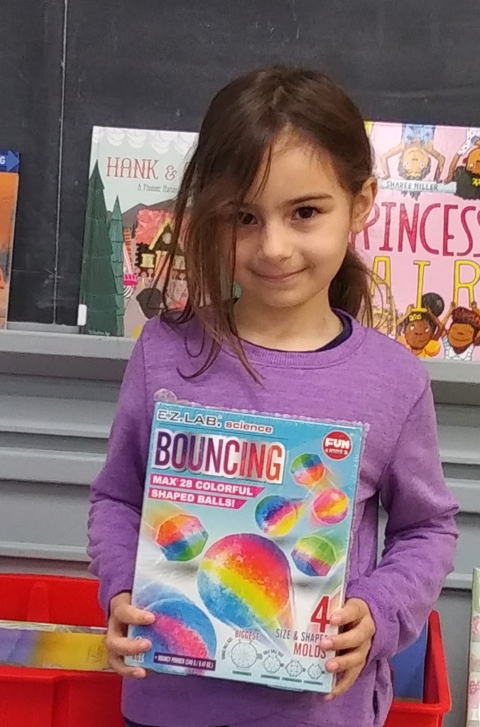 young brown-haired girl holding an elementary science book about bouncing