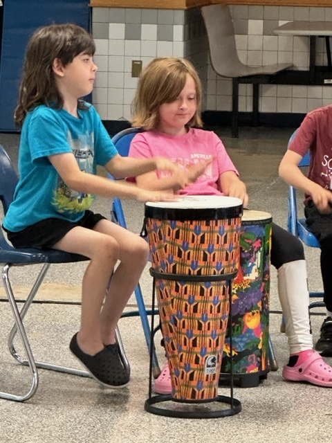 boy and girl in chairs playing african drums